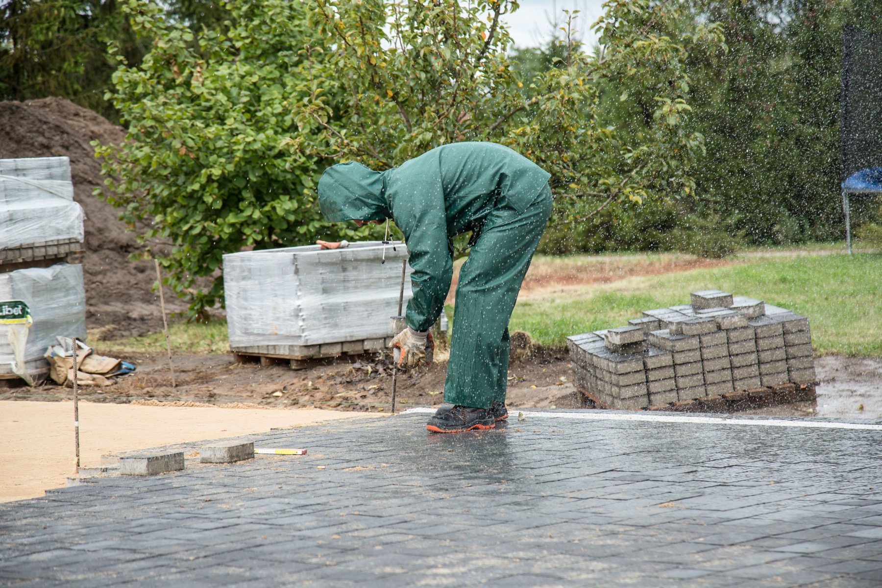 Worker installing interlocking paving stones