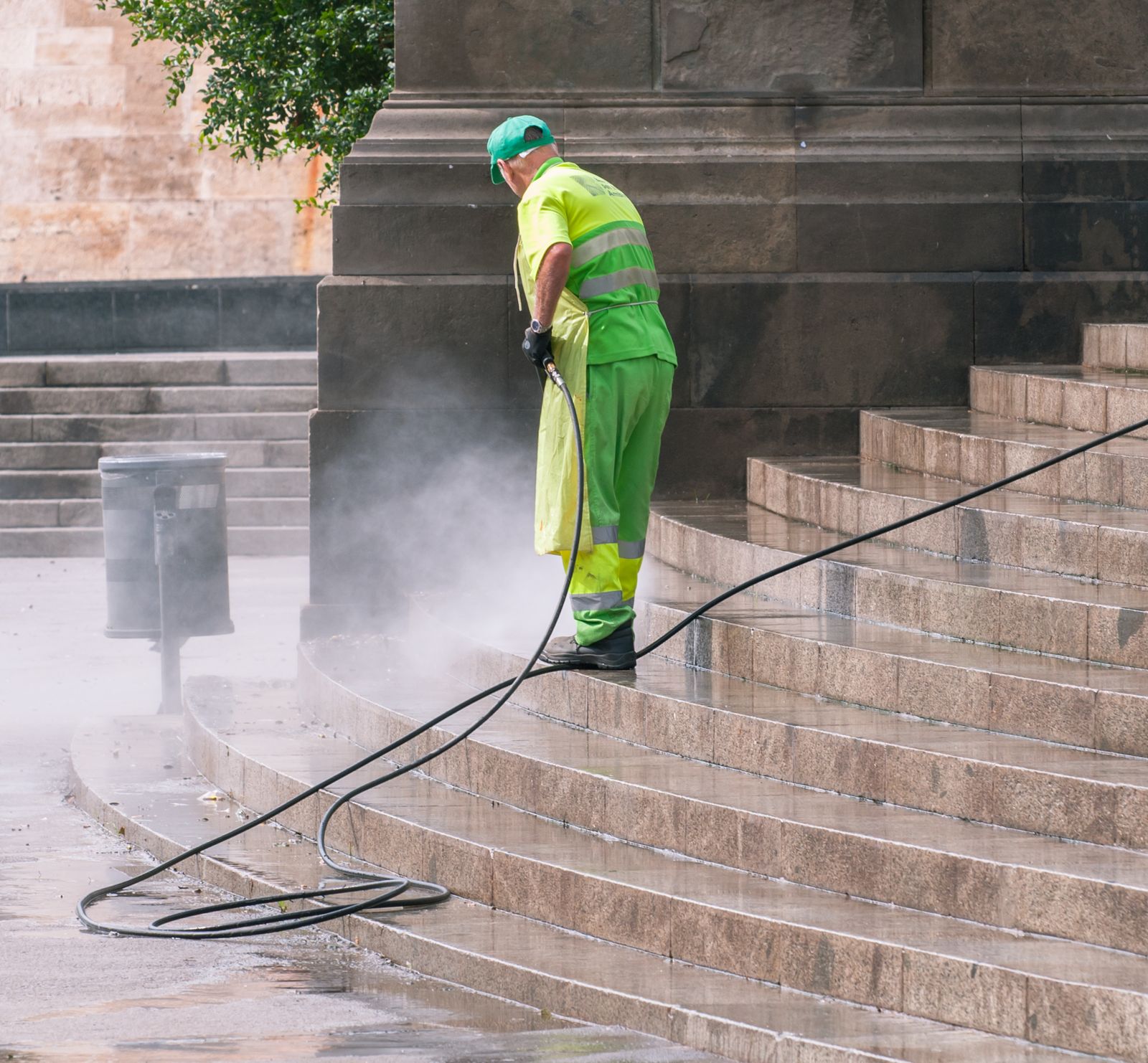 Worker pressure washing a paved surface